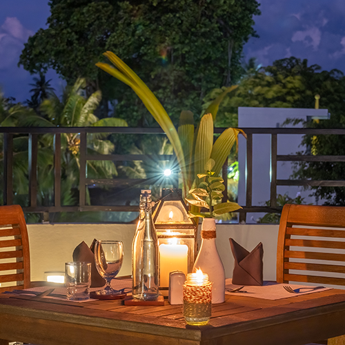 Illuminated table at the Kamadhoo Inn restaurant, outside at night with candles. Romantic setting table for two.